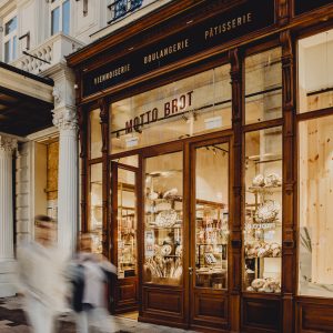 die hell erleuchteten Schaufenster der Bäckerei Motto Brot. Das Licht ist in warmen Farben gehalten und das Interieur wirkt einladend