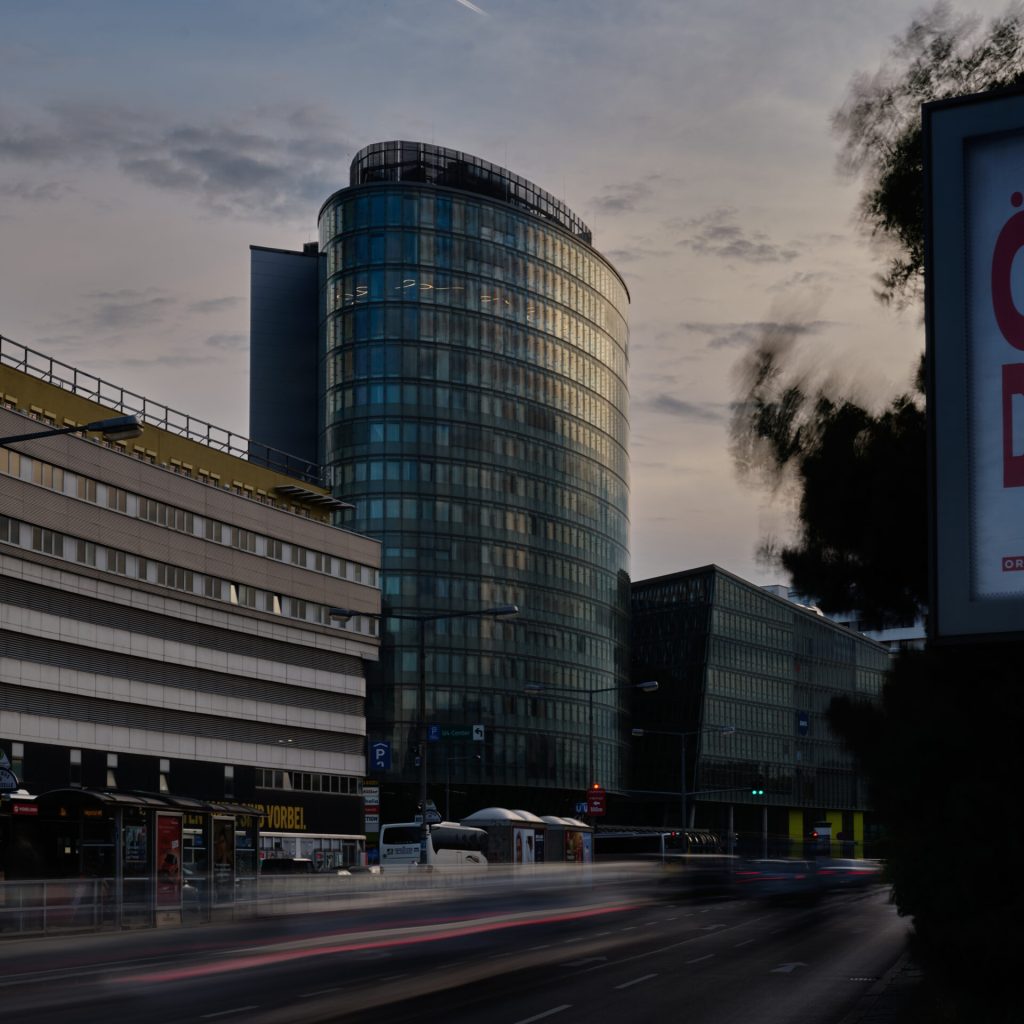 Außenansicht des Vio Plazas in Wien Meidling in der Abenddämmerung. Im 14. Geschoss illuminiert die floral angeordnete Liquid Line LED Leuchte die Räumlichkeiten